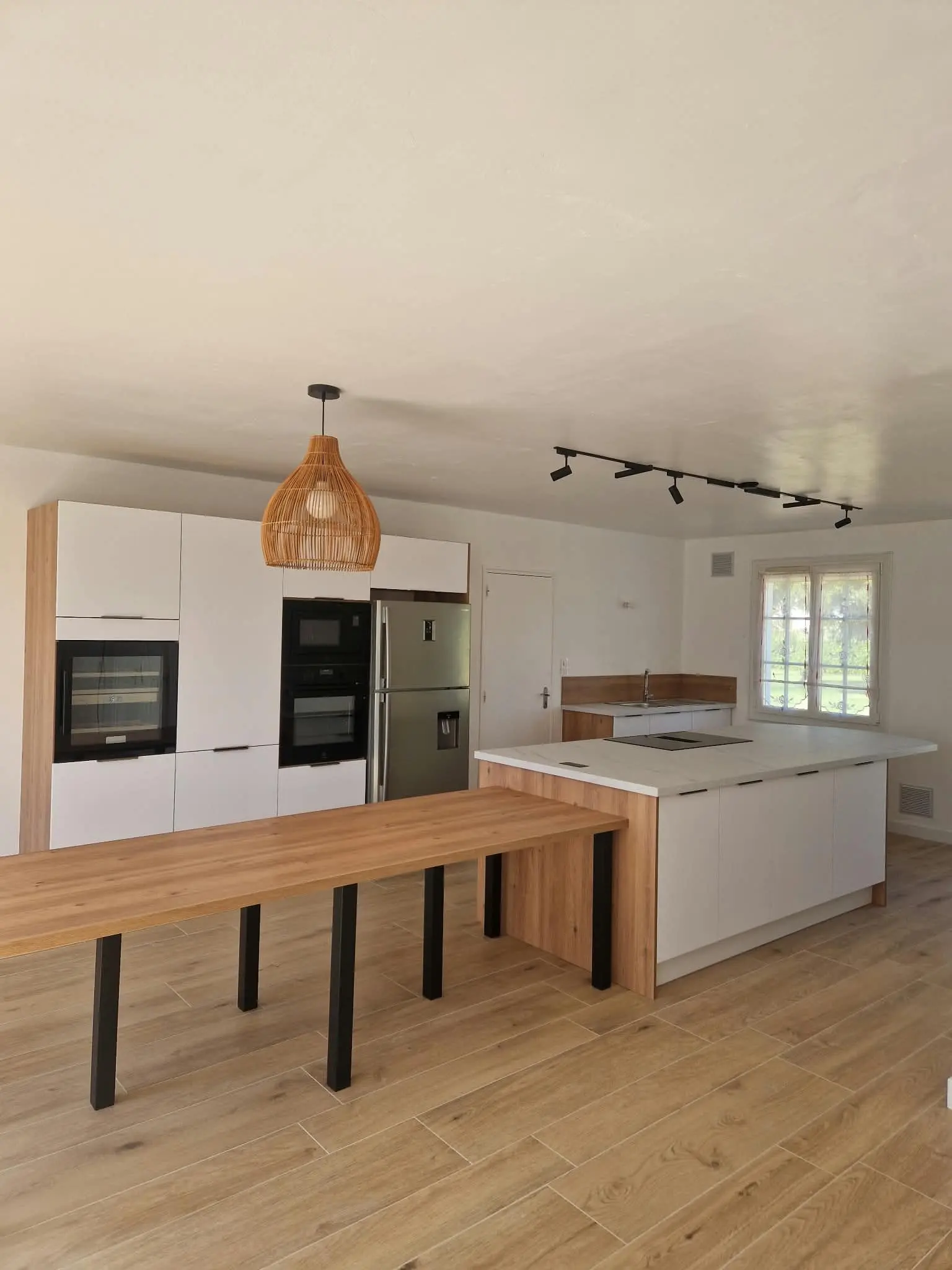 Cuisine blanche, îlot et longue table en bois